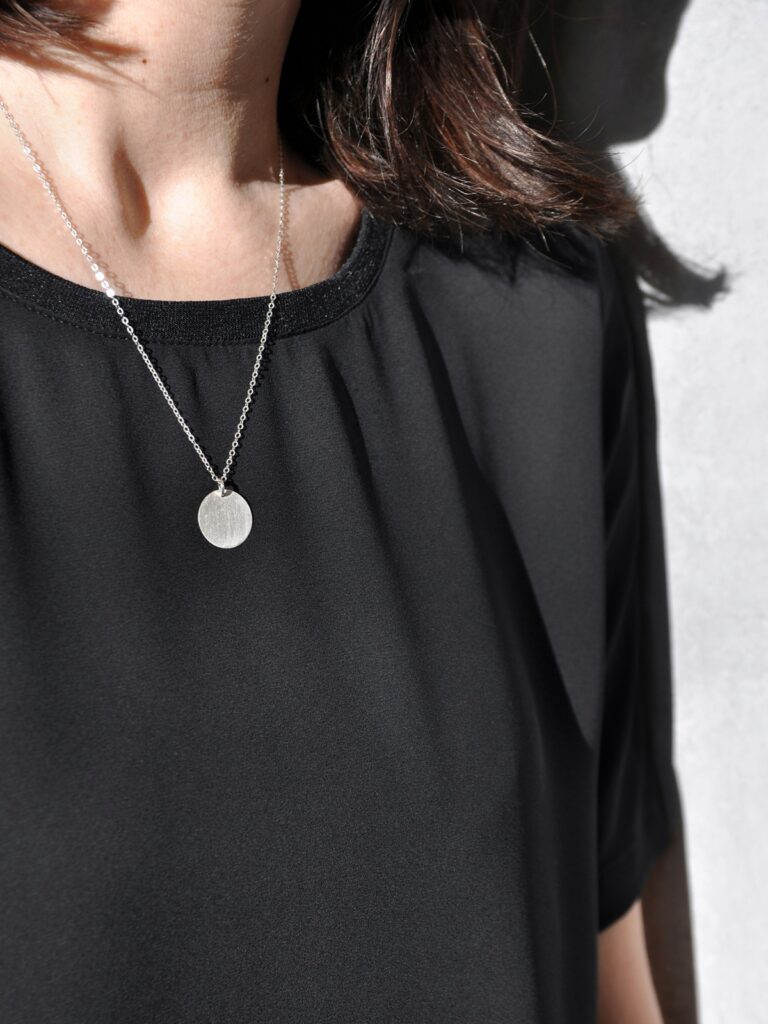 dekolt kobiety w czarnej bluzce i ze srebrnym naszyjnikiem z upcyklingu firmy czarnecka