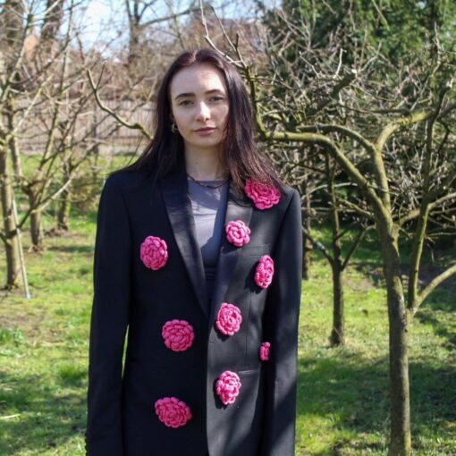 Modelka w parku nosi czarną marynarkę z upcyklingu ozdobioną różowymi kwiatami od Second Charm – ekologiczna moda zero waste
